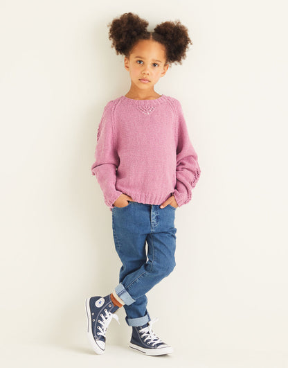 Child wearing a pink sweater, blue jeans, and black sneakers on a white background