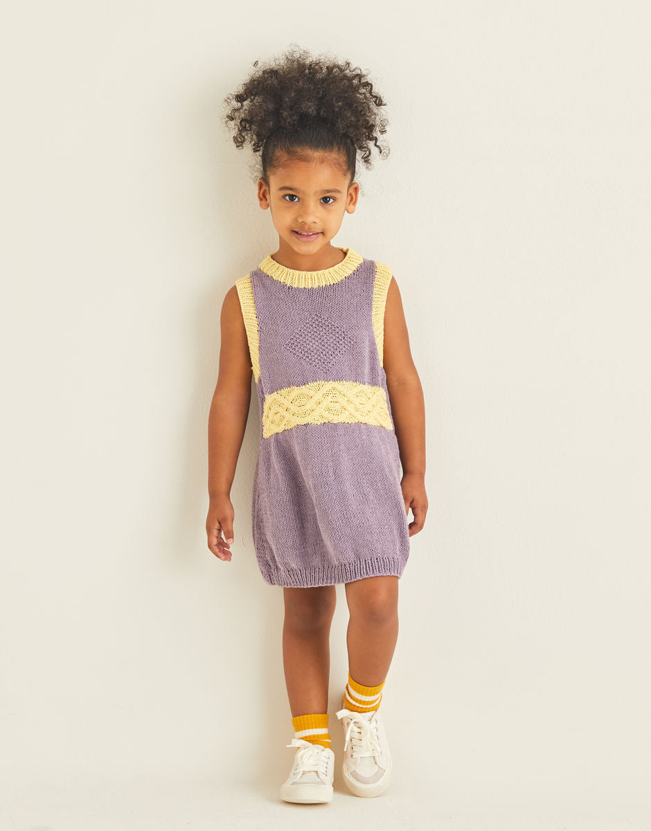 Young girl wearing a purple and yellow dress against a plain background