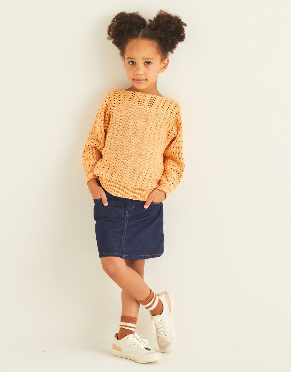 Child wearing a mustard yellow sweater and denim skirt on a plain background
