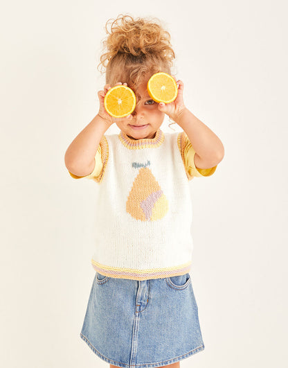 Child holding lemon slices over eyes wearing a sleeveless top with a pear design and denim skirt.