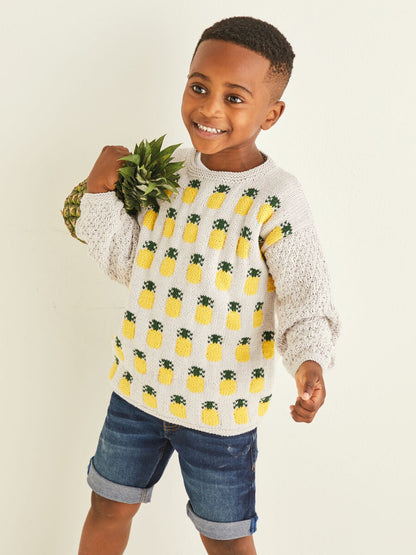 Child wearing a sweater with pineapple pattern holding a plant against a plain background