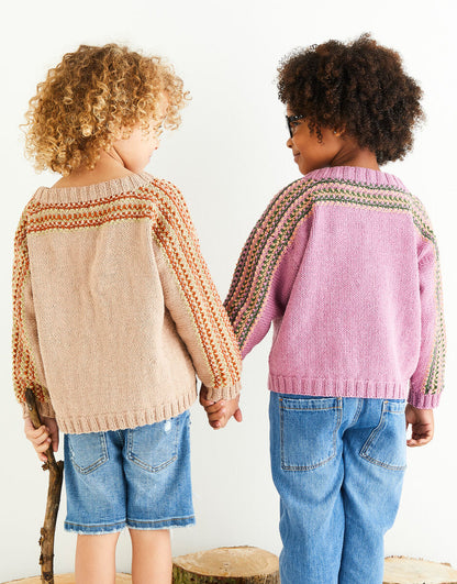 Two children wearing patterned sweaters holding hands against a white background