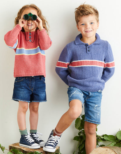 Two children wearing colorful sweaters with henley collars and a wide stripe and shorts standing next to each other.