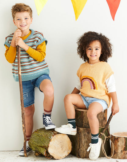 Two children in colorful sweaters standing next to wooden logs with a white background