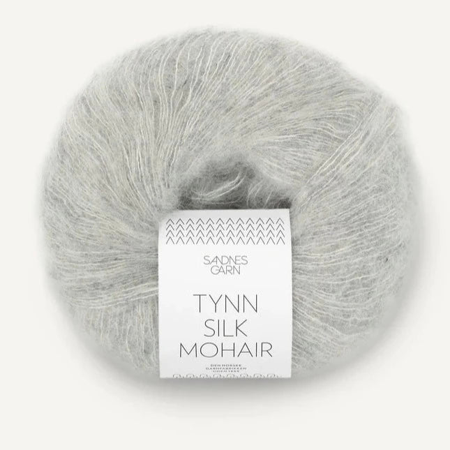 A ball of Tynn Silk Mohair yarn in a  light grey color with a 'Tynn Silk Mohair' label from Sandnes Garn