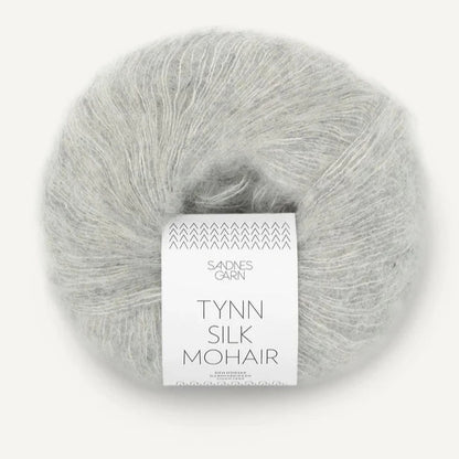 A ball of Tynn Silk Mohair yarn in a  light grey color with a 'Tynn Silk Mohair' label from Sandnes Garn