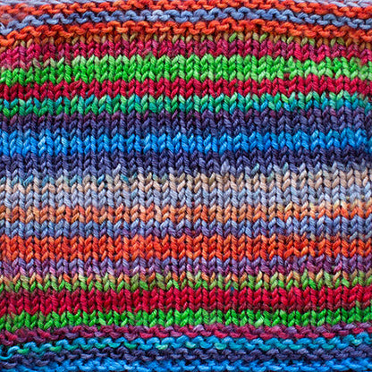 a knitted swatch of merino yarn with blue, green, red, and purple tones from Urth yarns