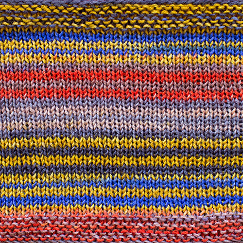 a knitted swatch of merino yarn with yellow, red, grey, and blue tones from Urth yarns