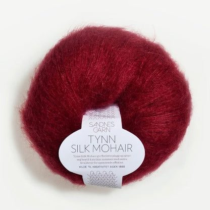 A ball of Tynn Silk Mohair yarn in a deep red color with a 'Tynn Silk Mohair' label from Sandnes Garn