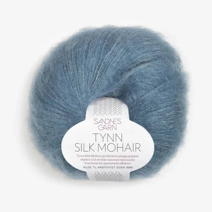 A ball of Tynn Silk Mohair yarn in a denim blue color with a 'Tynn Silk Mohair' label from Sandnes Garn
