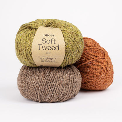 Three skeins of DROPS Soft Tweed yarn in beige, green, and orange colors, stacked on top of each other.